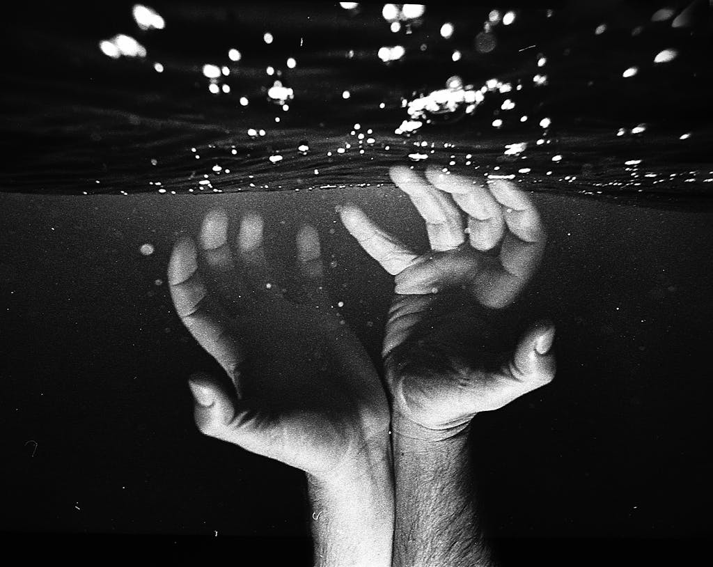 Hands of crop faceless man under water